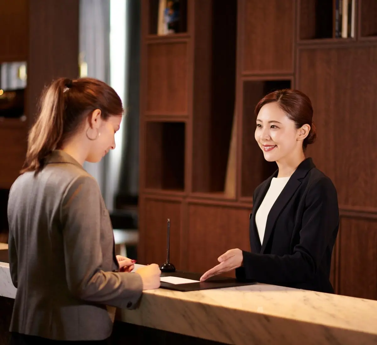 Rezeptionist und Gast im Gespräch - Symbolbild für die Betriebshaftpflicht für Hotels